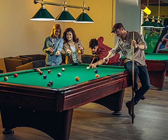 Shot of four friends playing billiards