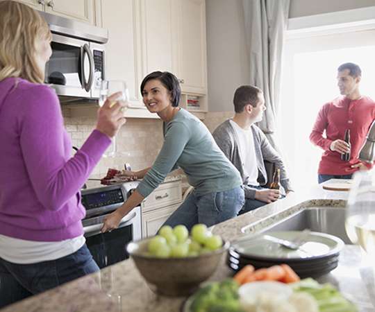 Group of friends gathered in domestic kitchen for dinner party